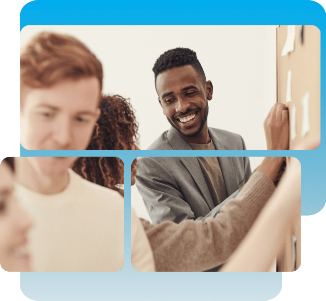 Three people are collaborating in an office, with one man smiling and placing sticky notes on a board while others look on.