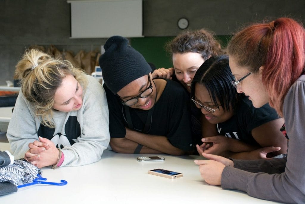 five women front of tables with two smartphones