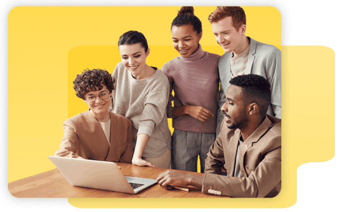 Five people stand and sit around a wooden table, looking at a laptop screen together, against a yellow background.